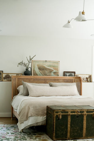 Rustic, beachy bedroom design with ceiling bedroom lamps, vintage trunk, and wicker bedframe.