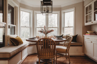 A cozy and inviting kitchen dining table design with wooden chairs, throw pillows.