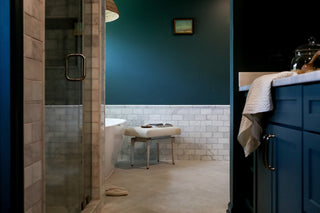 A bathroom design with blue walls and cabinets , a stepless shower and freestanding tub
