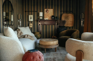 Vintage antique furniture in a plush and cozy living room set up with striped wallpaper and an area rug for living room