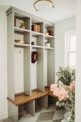 A mudroom designed with a bench, sitting area and a space to hang coats along with some shelving.