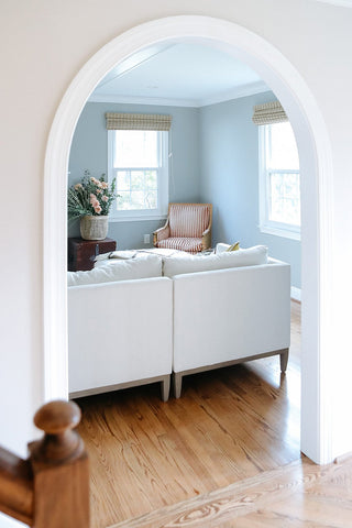 Round entry peering into a pastel living room theme with light blue walls.
