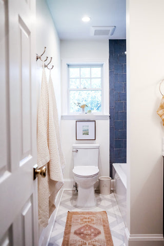 Clean and bright washroom design with dark blue tile in the shower.