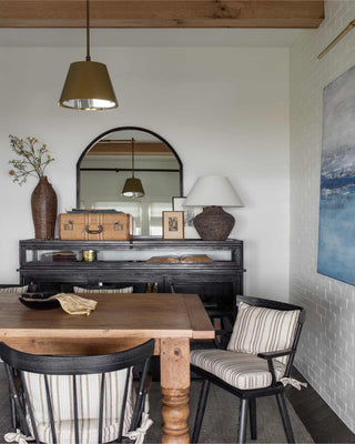 Rustic dining room with wooden table and chairs, dark hardwood accents and arched mirror