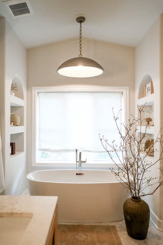 A warm and calming bathroom design with a freestanding tub with natural textures.