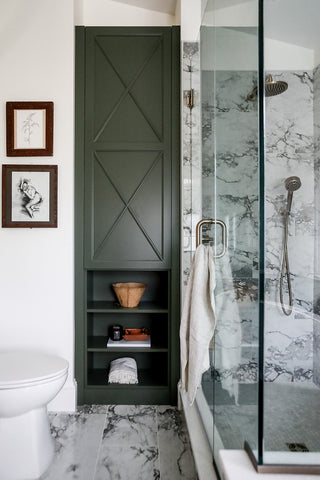 Marble floors and shower with a dark green cabinet bathroom design.