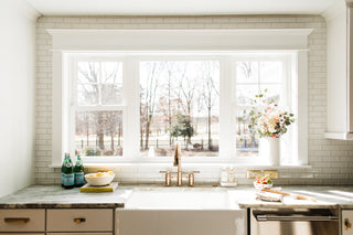 A kitchen with a farmhouse sink, marble countertops, and copper hardware that was designed using virtual design services