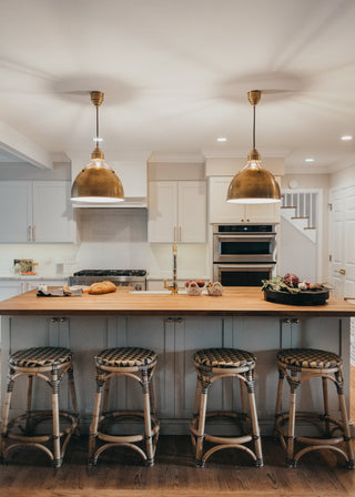 A kitchen island with woven seating and hanging lights.