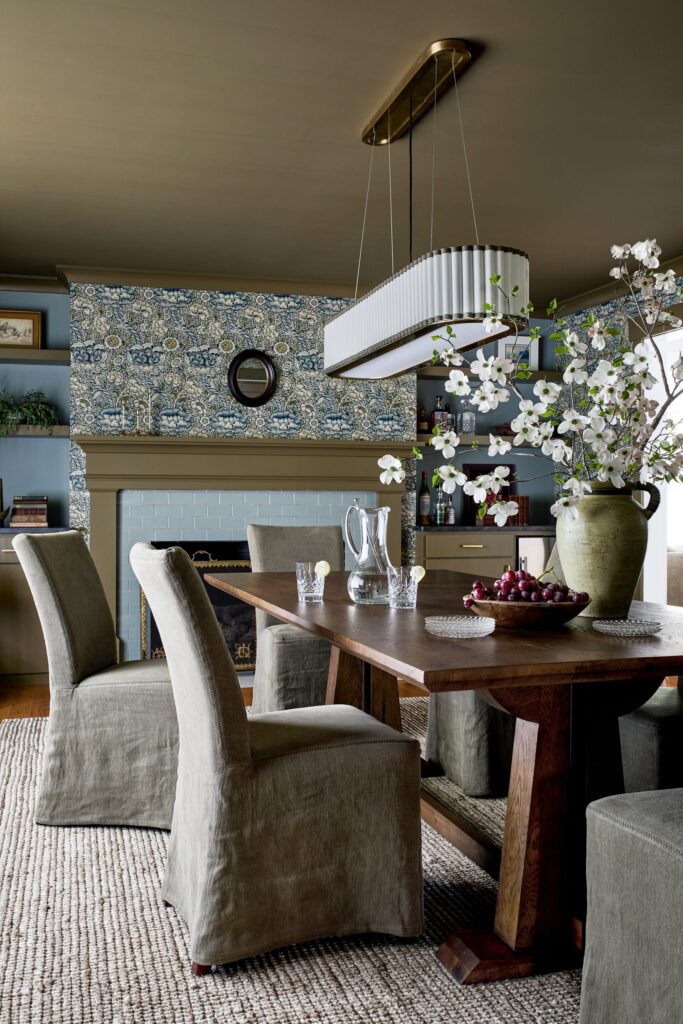 Dining room with layered blue wallpaper and neutral linen chairs — Details + Design interior design.