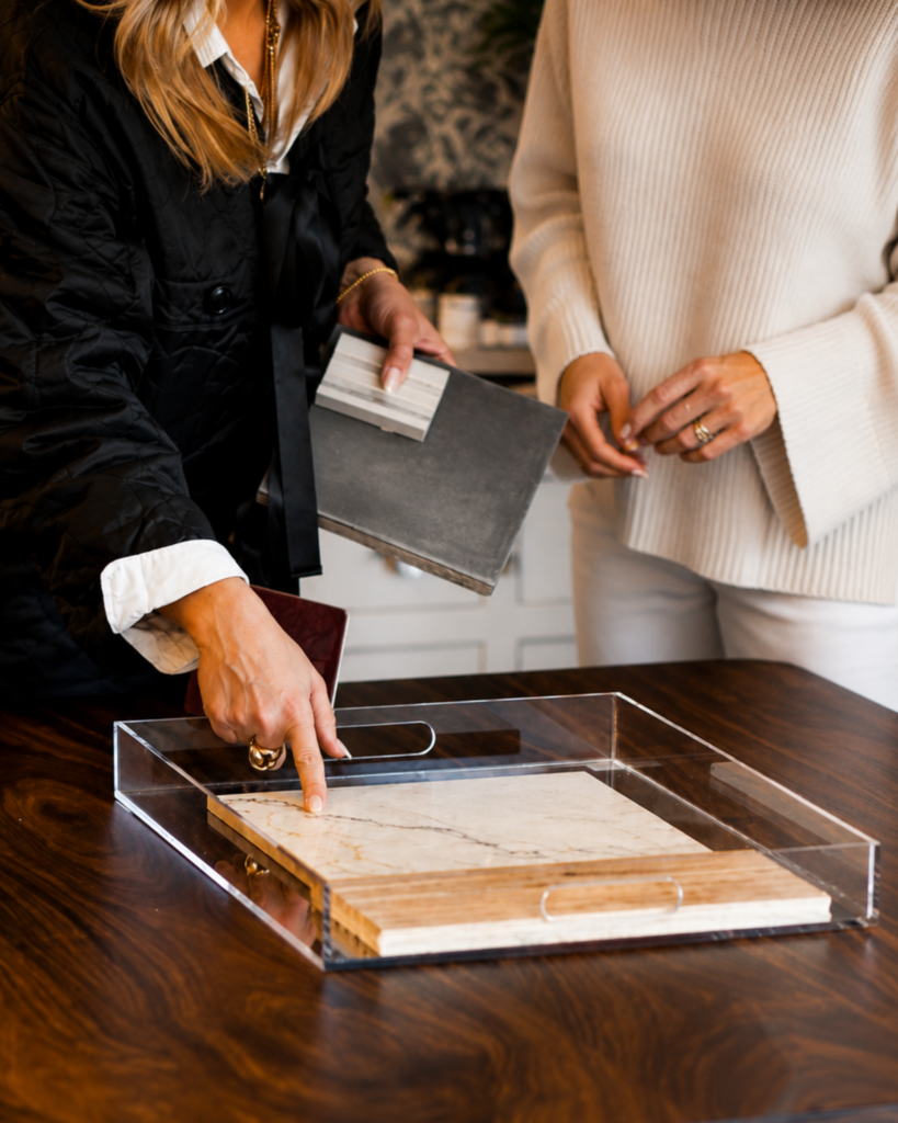 Interior designer reviewing finish and stone samples with a client, demonstrating when to hire an interior designer for new construction before major material and design decisions are finalized.